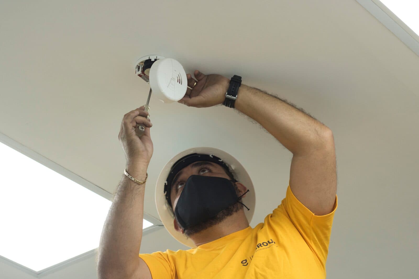 Instalador colocando un dispositivo en plafón.